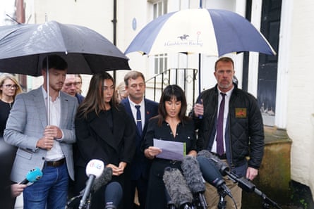 A family stand under umbrellas, speaking to teh press after an inquest at Wiltshire and Swindon Coroner's Court in Salisbury