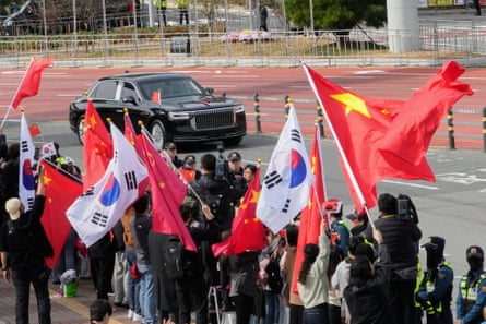People wave South Korea and China flags as a car drives past