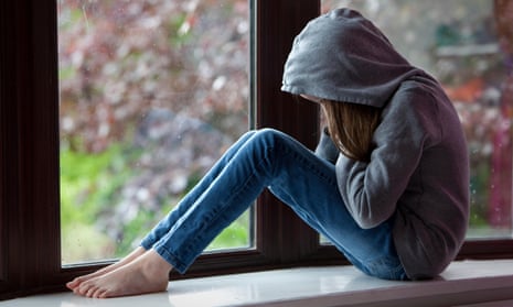 girl in hoodie sits on window ledge