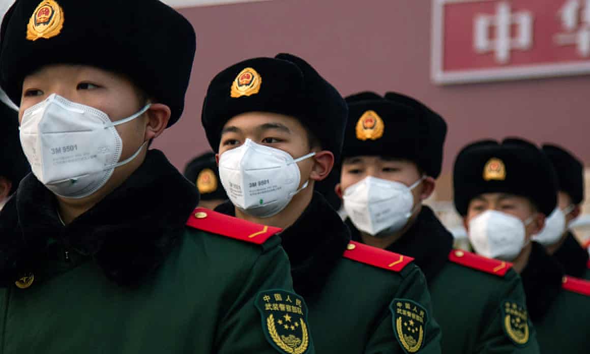 Chinese police officers wearing masks stand in front of the Tiananmen Gate Sunday.