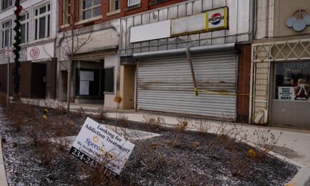A street in Youngstown, Ohio, with a shuttered shops with a Pepsi sign and a sign reading “Looking for addiction treatment” stuck in slightly snowy ground