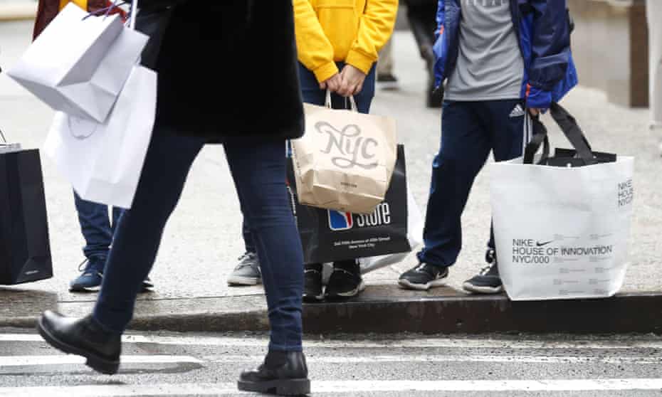 People hold shopping bags while walking on Fifth Avenue in New York City in November. 
