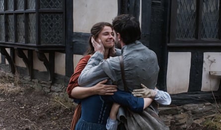 Jessie Buckley and Paul Mescal embrace in front of a Tudor building in the film Hamnet