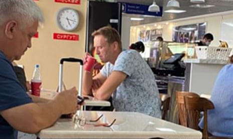 Alexei Navalny drinking from a takeaway cup at the Vienna cafe at Tomsk airport.