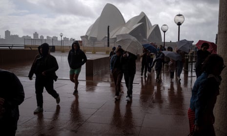 People shelter from a heavy rain and wind as they visit the Sydney Harbour waterfront on 30 September.