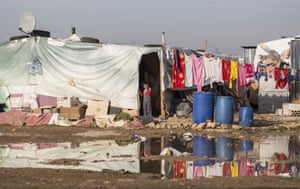A young refugee looks out of his makeshift home across flooded land in the Bekaa