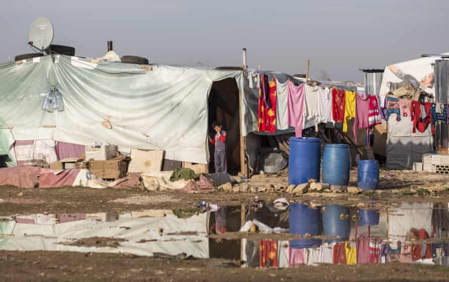 A young refugee looks out of his makeshift home across flooded land in the Bekaa