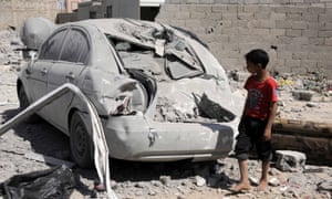 A child looks at a damaged car at the scene of an airstrike in Sana’a