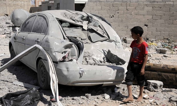 A child looks at a car damaged in an airstrike in Sana'a, Yemen