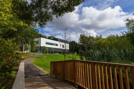 A gallery seen from a distance beyond grass and trees