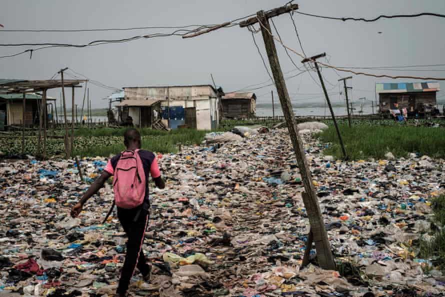 A man walks on plastic waste in the Mosafejo area of Lagos on 12 February 2019.