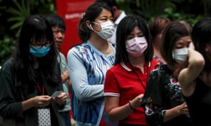 Office workers wear protective masks while queueing to collect hand sanitiser in Singapore.