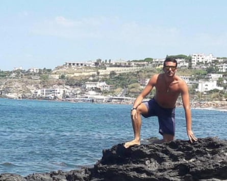 Marine biologist Federico Gualtieri crouching on rocks with the sea behind.