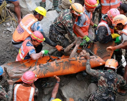 Rescue workers surround survivor on orange stretcher, all covered in mud