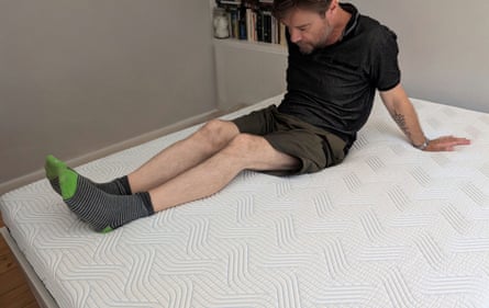 The review’s husband lies on the Tempur Pro Plus SmartCool mattress and inspects its firmness.