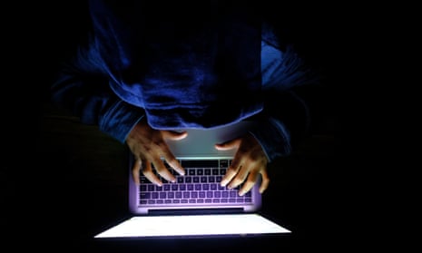 Hooded hacker with laptop stealing personal data from internet.