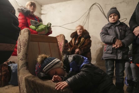 A child sleeps in an armchair as others stand around in a shelter during Russian shelling in Mariupol, 24 February.