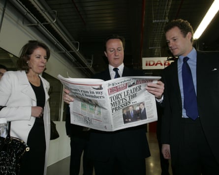 Cameron stands in the middle holding open a copy of the newspaper, flanked by Rothermere on one side and an unnamed woman on the other