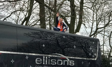 A Blackpool fan sits on top of the Arsenal team bus, preventing it from leaving their hotel on time.