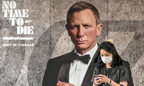 A woman with a face mask passes a poster for the new James Bond movie No Time to Die in Bangkok.