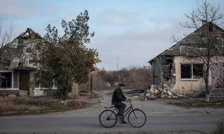 A local resident rides a bike near destroyed houses in the village of Arkhanhelske, Kherson region