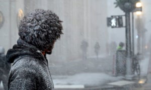 A New Yorker waits to cross a street during heavy snow fall in downtown Manhattan