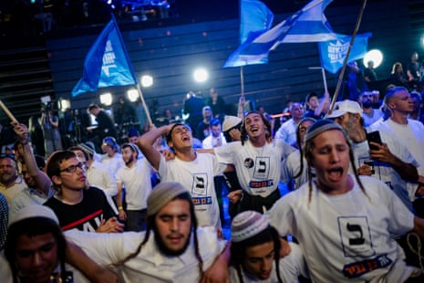 Otzma Yehudit supporters cheer and wave flags at an election night rally