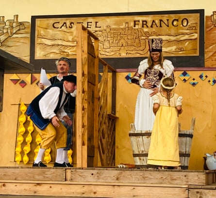 Various people on a wooden stage wearing traditional costume