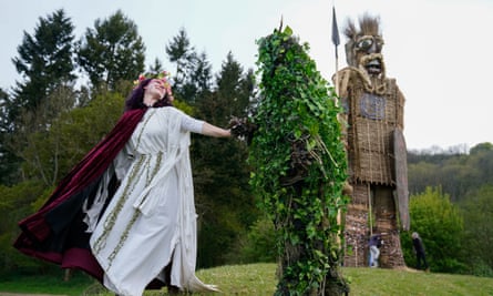 The Butser May Queen and Green Man dance in front of a giant wicker man at Butser Ancient Farm.