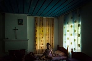 A young girl sitting on the bed with soft light coming in the window