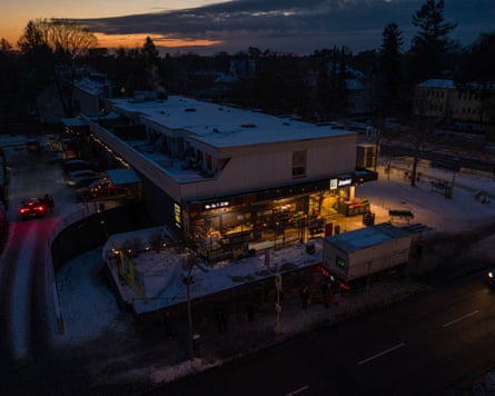 In a very dark scene the front of the supermarket is illuminated with lights