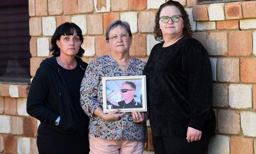 L-R: Claire Brosnan, mother Joy Hobbelen, and Suellen Brosnan with a photo of missing son and brother Nathan Brosnan.