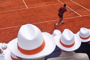 Spectators sporting the same hat look on as Giovanni Mpetshi Perricard returns the ball to Damir Dzumhur