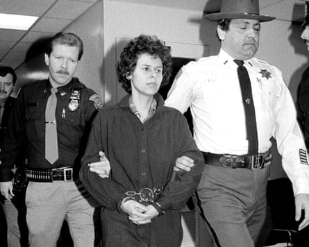 A handcuffed woman is escorted by police officers into a building