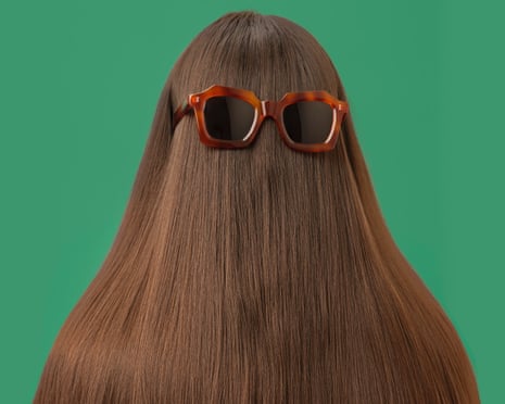 Orange-framed sunglasses sit atop long straight hair, worn upside down covering the face