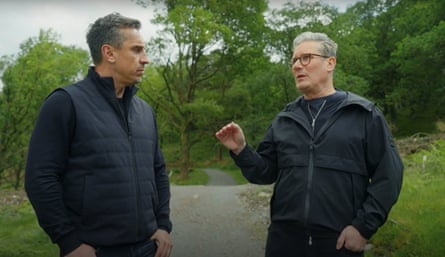 Gary Neville and Keir Starmer walking outdoors: Starmer is speaking and gesturing with one hand