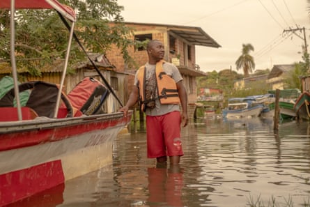 A man wades next to a boat down a flooded street