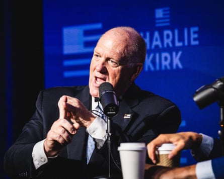 Tom Homan, wearing a suit, speaks into a microphone in front of a Charlie Kirk podcast banner.