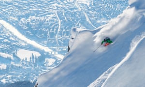 freeride skier on steep slopes with the city in the distance