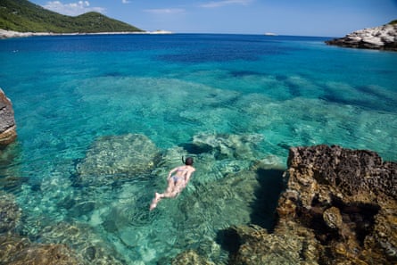 Woman snorkelling in clear blue water over rocks