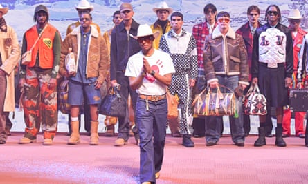 Pharrell Williams on stage with people behind him some with western-type hats