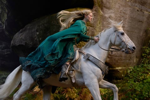 film still of a woman in a green cloak riding a white horse