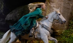 film still of a woman in a green cloak riding a white horse