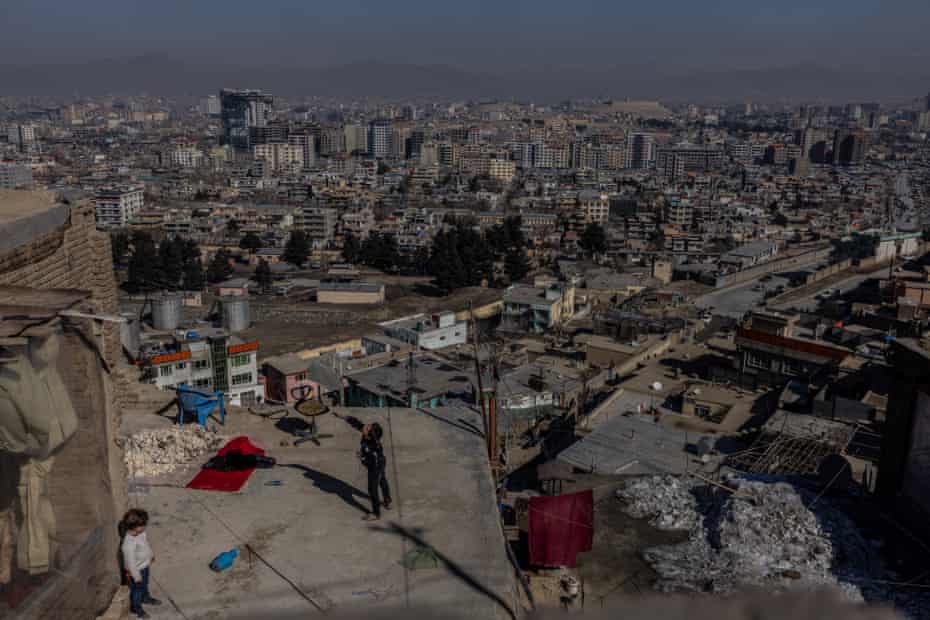 A boy flying his kite from a rooftop in Kabul