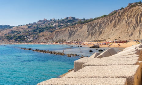 High rocky cliffs and the promontory frame the blue sea and the sandy beach at Licata, Sicily