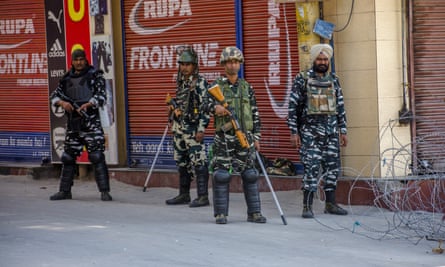 Indian paramilitary troopers stand guard in front of shuttered shops in a deserted square in Srinagar.