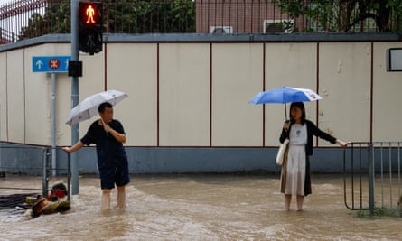 People hold railing for stability in a flooded area of Hong Kong