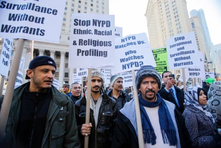 People in a crowd hold signs that say ‘stop NYPD ethnic, racial & religious profiling’