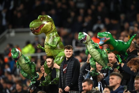 Newcastle United fans carry T-Rex inflatables to taunt the Everton goalkeeper Jordan Pickford for supposedly having short arms.