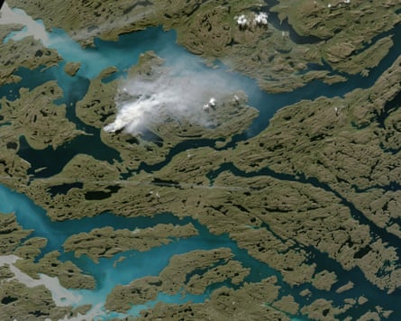 Aerial photograph of white smoke rising from a region of green vegetation